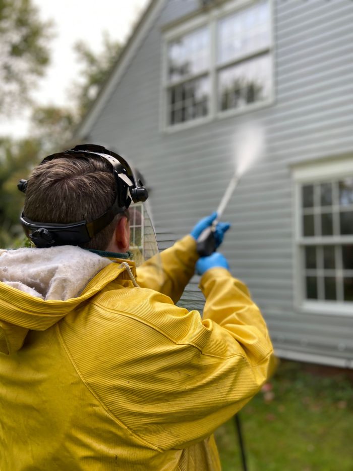 Worker powerwashing the siding of a house